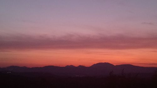 Scenic view of silhouette mountains against romantic sky at sunset