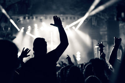 Silhouette people at music concert against sky at night