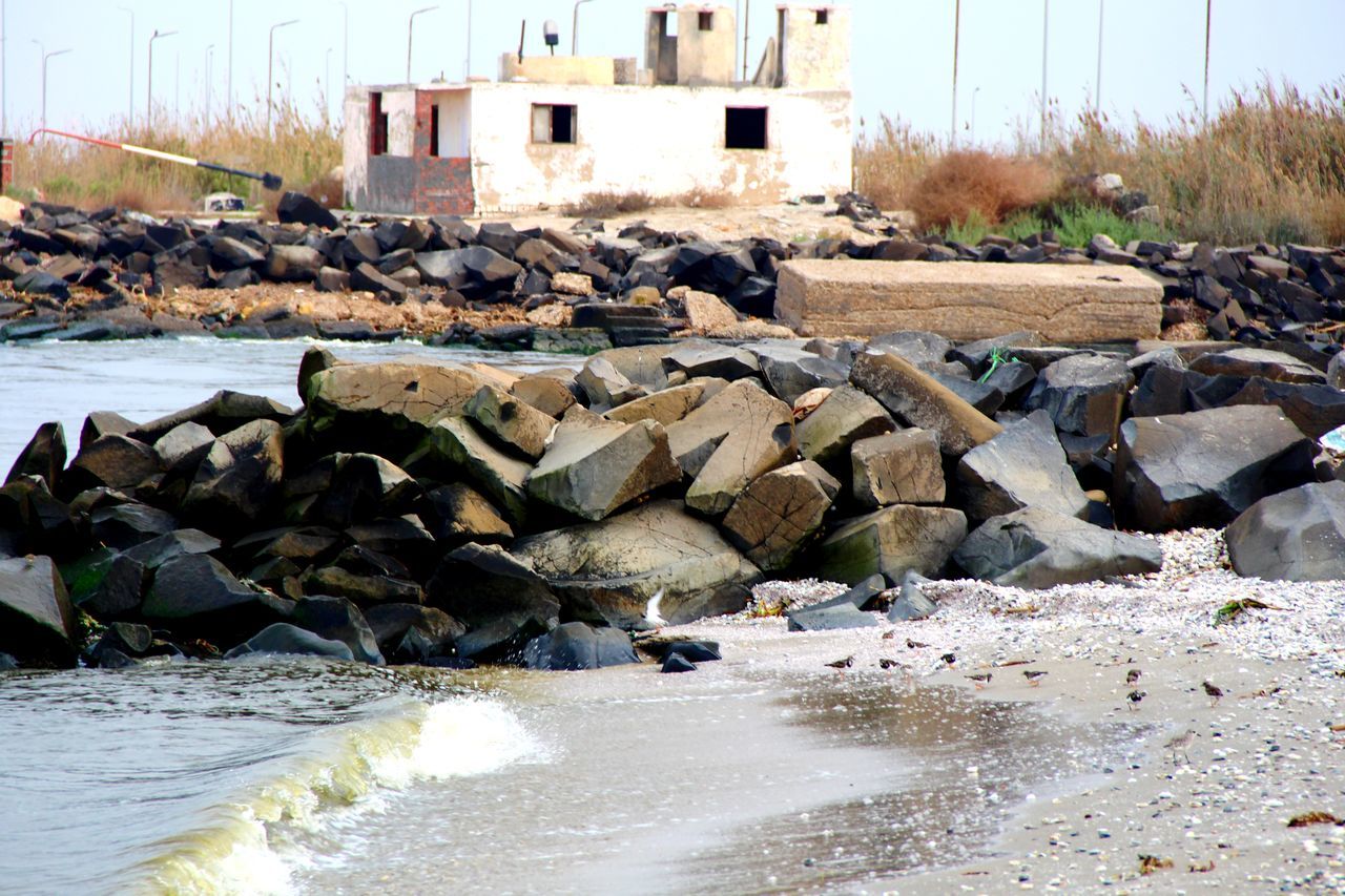 water, nature, built structure, architecture, day, sea, shore, building exterior, no people, land, rock, coast, building, outdoors, beach, sky, sunlight