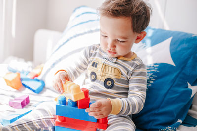 Cute baby toddler playing building with learning toy stacking blocks at home. early age education mo