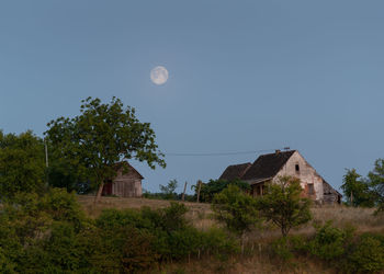 Houses and trees on field against sky