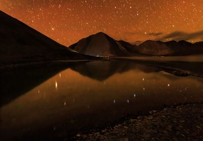 Scenic view of lake and mountains against sky at night