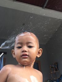 Portrait of cute shirtless baby boy bathing in back yard