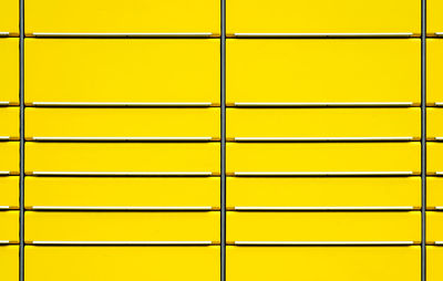 Full frame shot of yellow wall seen through metal grate