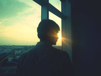 Rear view of a man looking through window