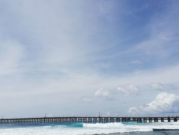 Pier on sea against cloudy sky