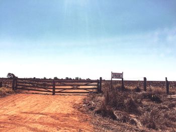 Information sign by closed gate against blue sky