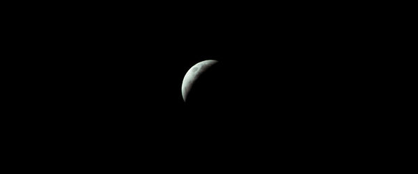 Low angle view of half moon against black background