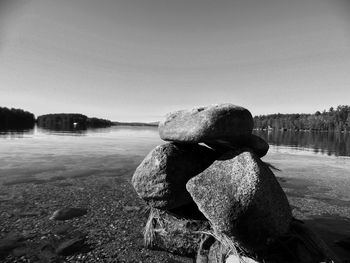 Rocks at lakeshore against clear sky