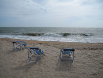 Chairs on beach against sky