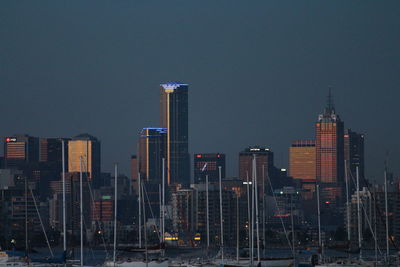 Sailboats moored in harbor against skyline at dusk