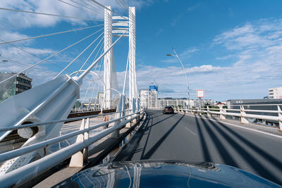 View of white cable bridge in city against sky