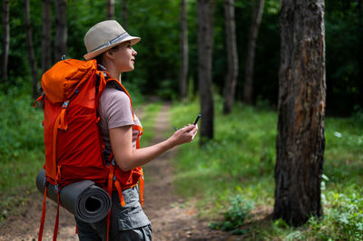 Side view of young woman standing in forest