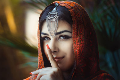 Portrait of smiling young woman with finger on lips