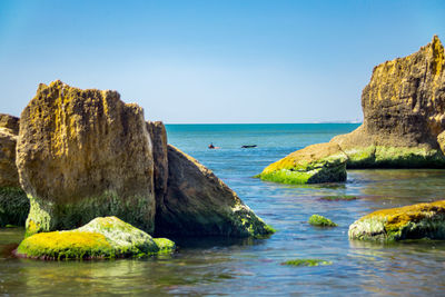 Scenic view of rocks in sea against clear sky