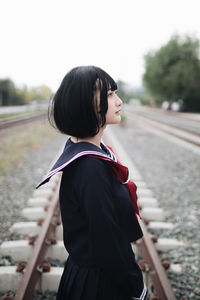 Rear view of woman standing on railroad track