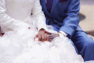 Midsection of bridal couple sitting outdoors