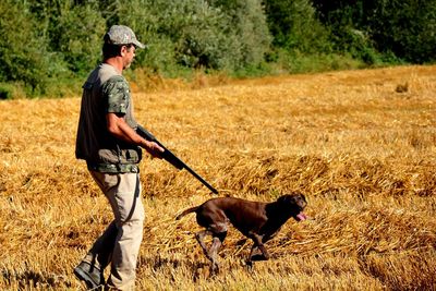 Side view of hunter walking with dog on land