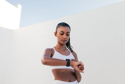 Young woman exercising against wall