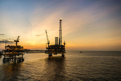 Silhouette of oil production platform during sunset at offshore oil field