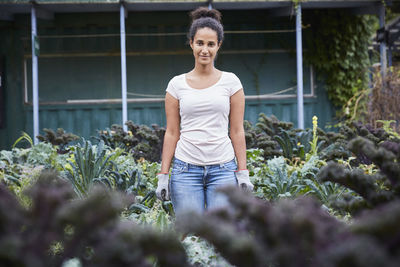 Portrait of gardener standing amidst plants