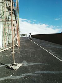 Side view of woman standing on road by building