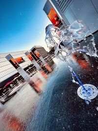 Information sign on street by buildings against sky