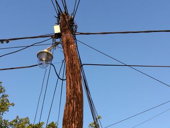 Low angle view of electricity pylon against clear sky