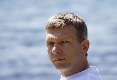 Close-up portrait of man against sea on sunny day