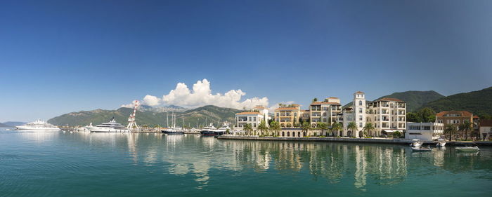 Buildings by sea against blue sky