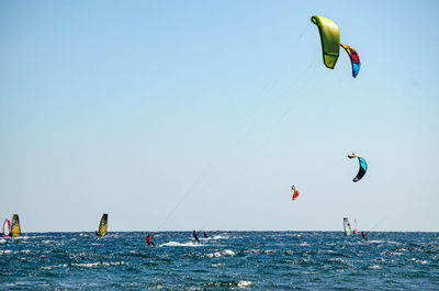 People paragliding over sea against clear sky