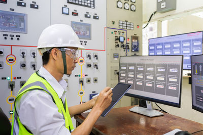 Male engineerr working in electrical control room in the heavy factory. 