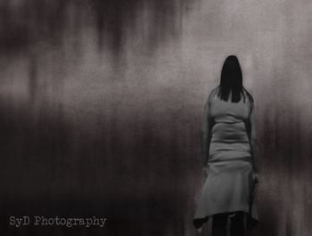 Rear view of woman standing against wall