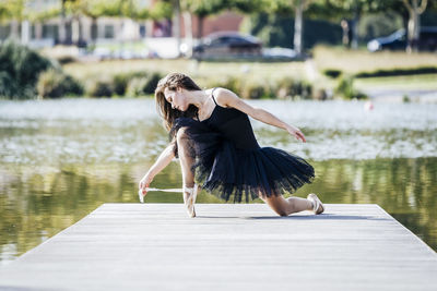 Woman ballet dancing on pier over lake