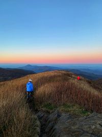 Rear view of person on field against sky during sunset atop tennent mountain in north carolina