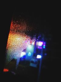 Illuminated street lights seen through wet glass window