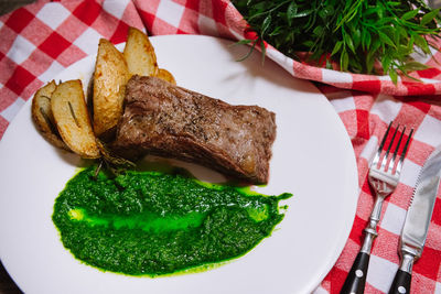 Picanha steak with green chimichurri sauce and country-style baked potato slices