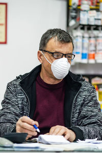 Man wearing mask sitting at counter in store