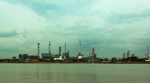 View of factory by sea against sky