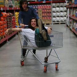 Portrait of boy pushing girl in shopping cart at store