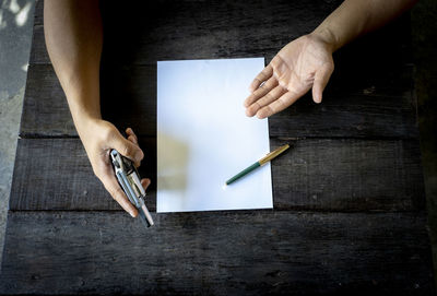 Close-up of businessman with gun and paper on table 