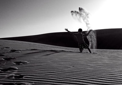 Boy throwing sand at desert 