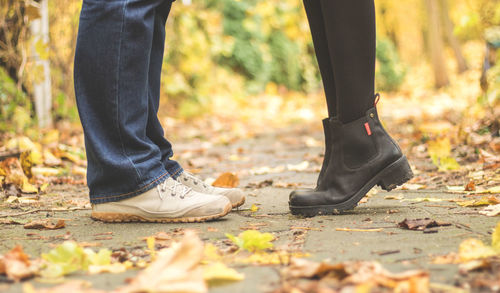 Low section of man standing on autumn leaves