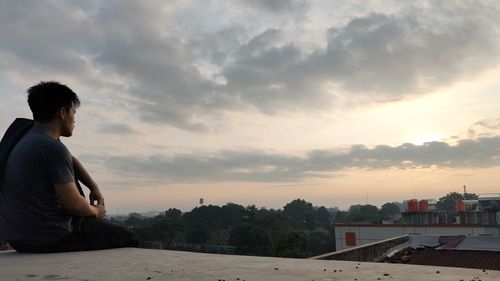 Side view of young man looking at sunset