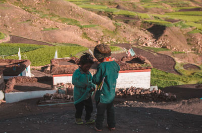 Rear view of friends standing at farm