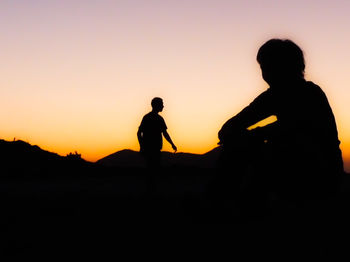 Silhouette children playing against sky during sunset