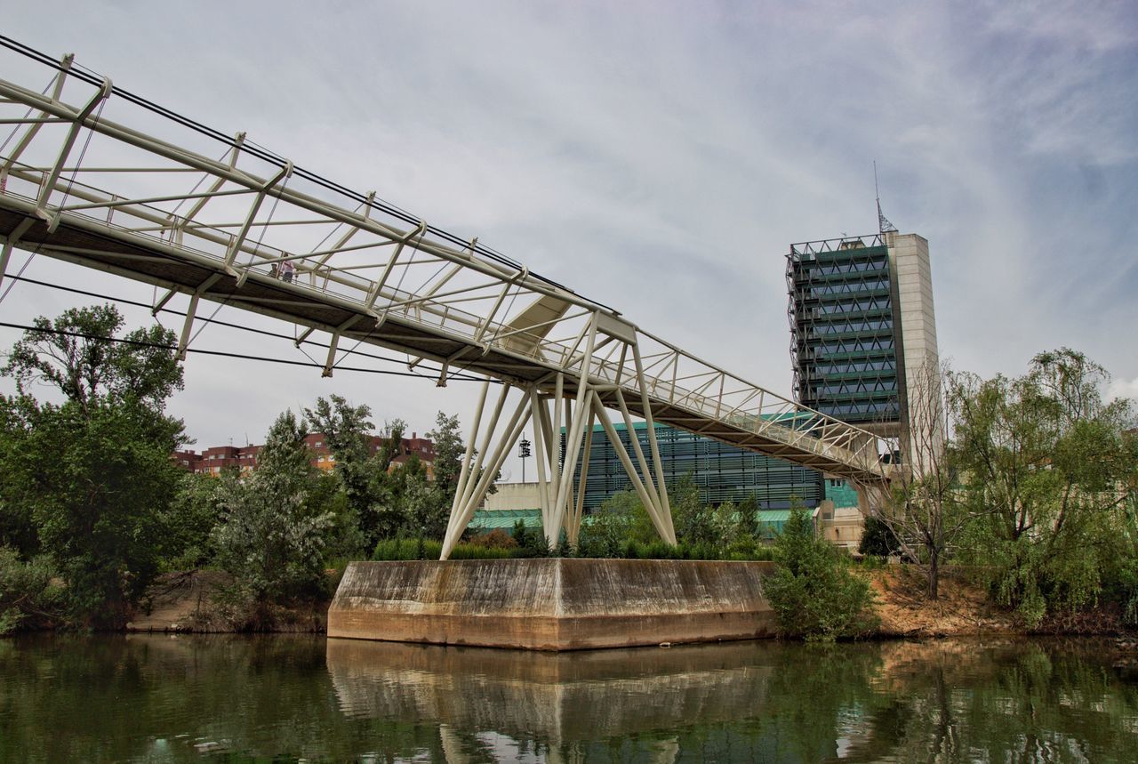 LOW ANGLE VIEW OF BRIDGE OVER RIVER AGAINST SKY IN CITY