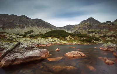 Rocks on shore by lake against sky in retezat mountains 