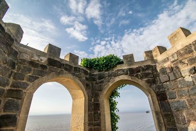 Low angle view of arch bridge against cloudy sky