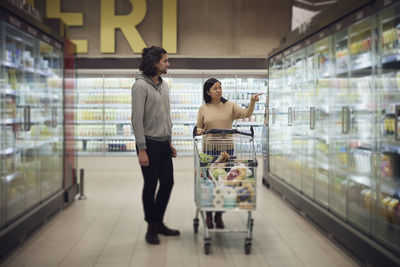 Couple standing in supermarket and talking while shopping